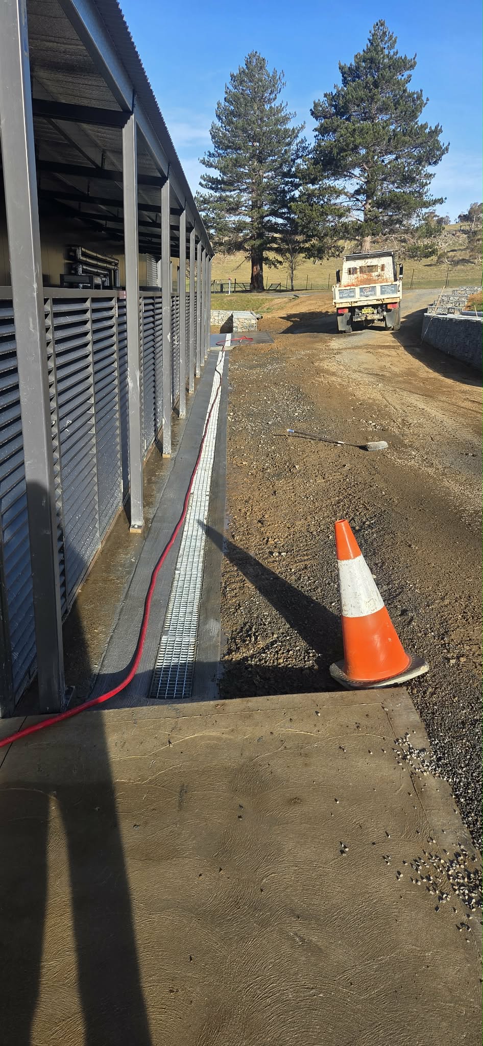 Grated channel drain installed along the edge of a building.