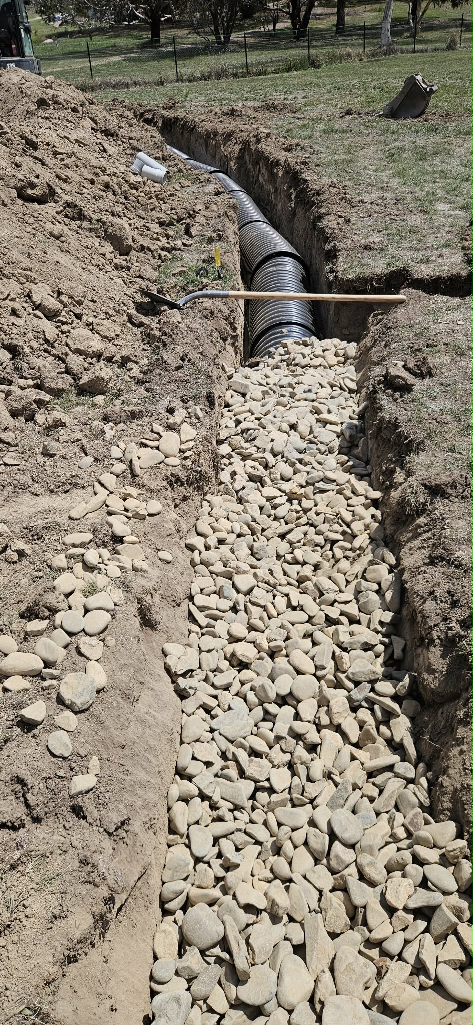 Excavated trench with drainage chambers and aggregate.