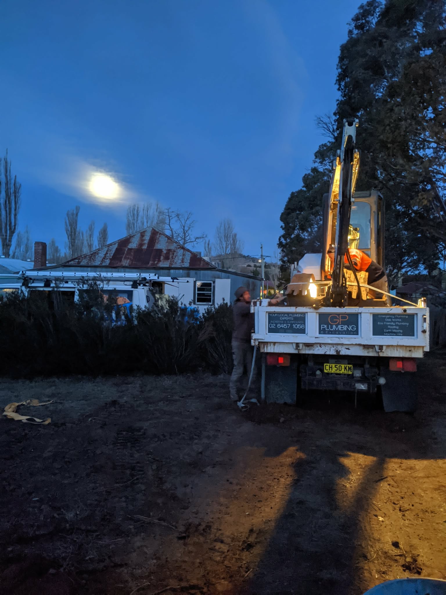 GP Plumbing truck and excavation equipment on site at dusk.
