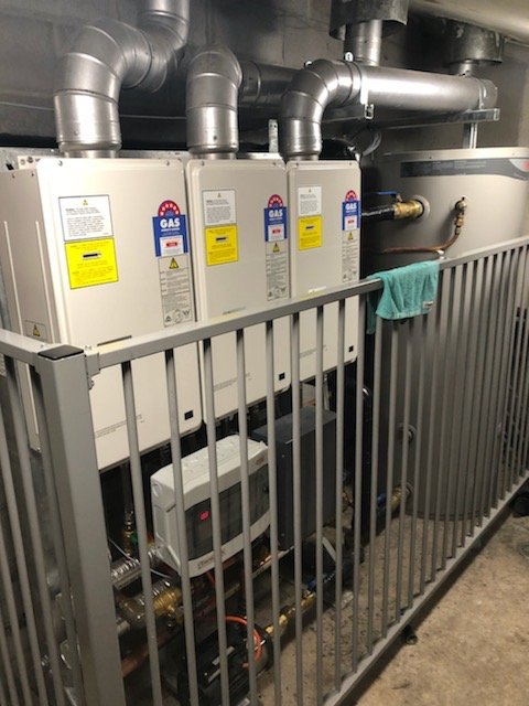 Multiple gas hot water units with flue connections and storage equipment.