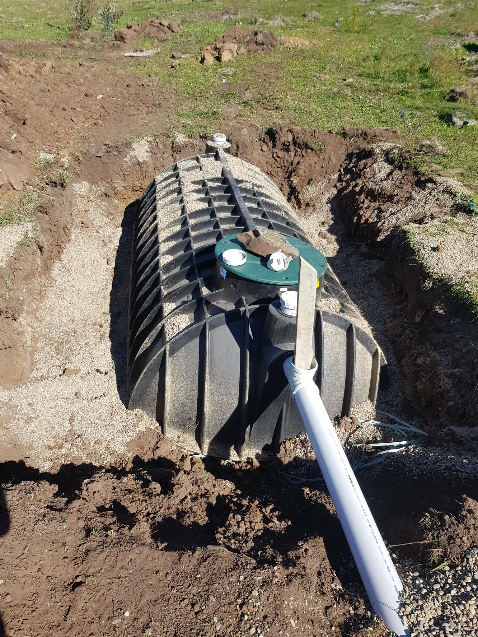 Underground tank positioned in an excavation with connected pipework.